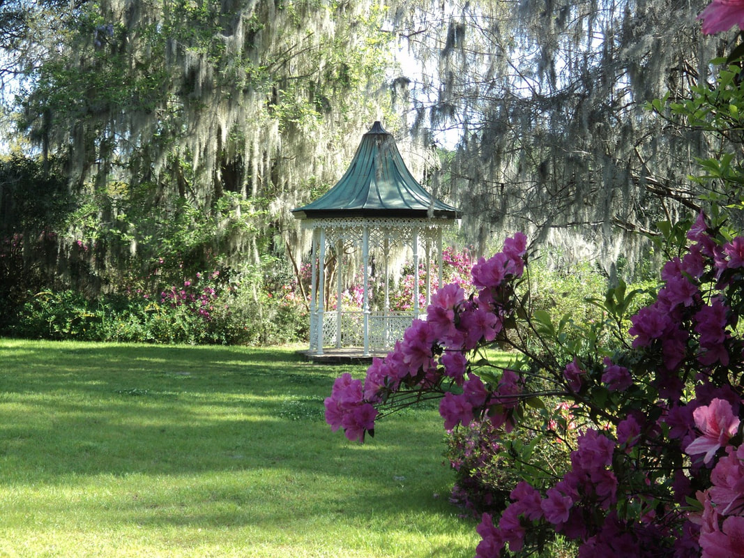 a gazebo surrounded by bushes and a lawn